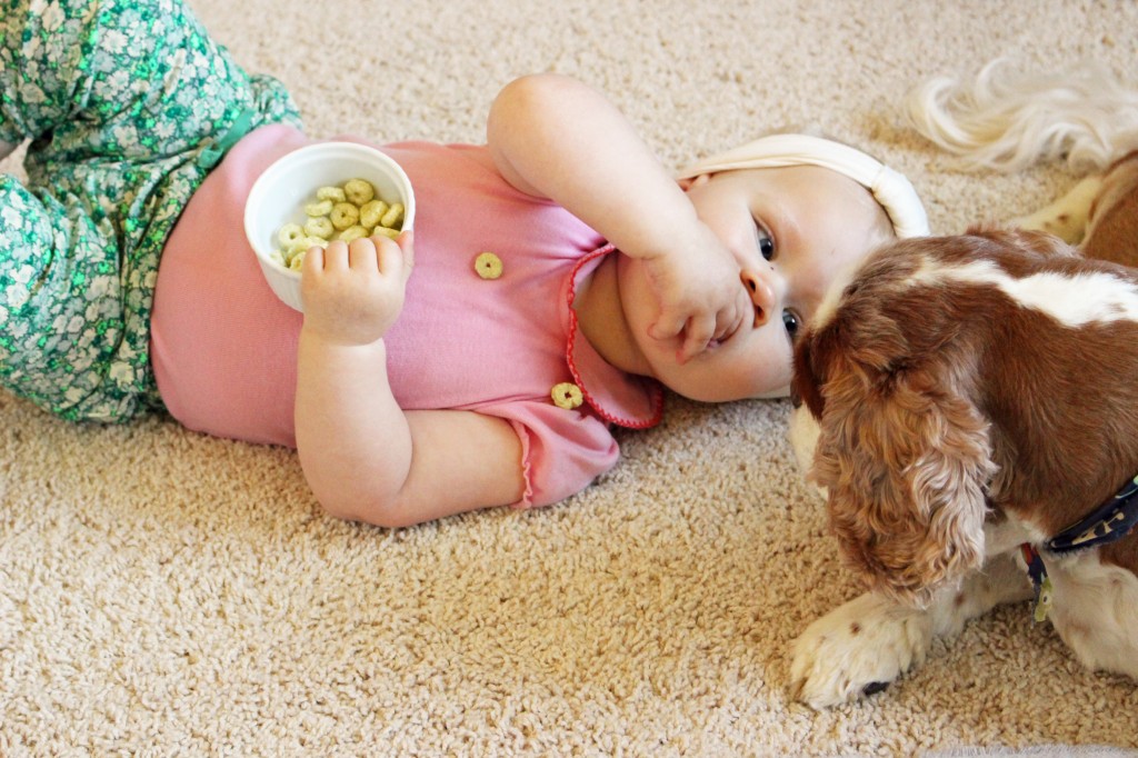 baby and her dog eating snacks